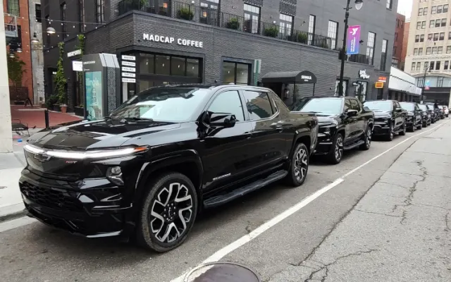 A row of black pickup trucks shown parked in downtown Detroit.