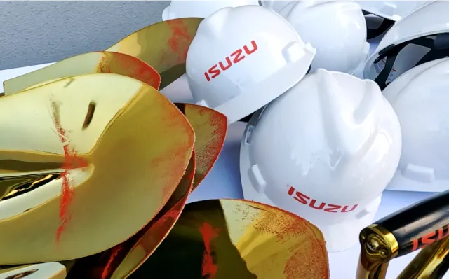 A collection of Isuzu hardhats and shovels, which have a dusting of red dirt.