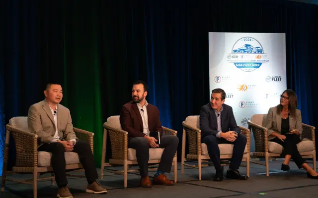 Four people sitting on stage doing presentation.