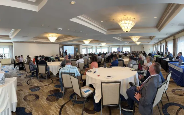 People in hotel conference room watching a speaker. 