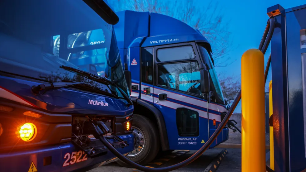 An electric truck is hooked upat a depot at night