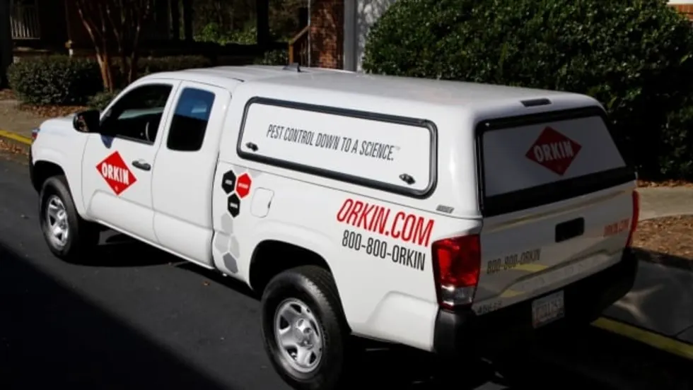  White Orkin-branded Toyota Tacoma service truck with a covered bed parked along a curb.