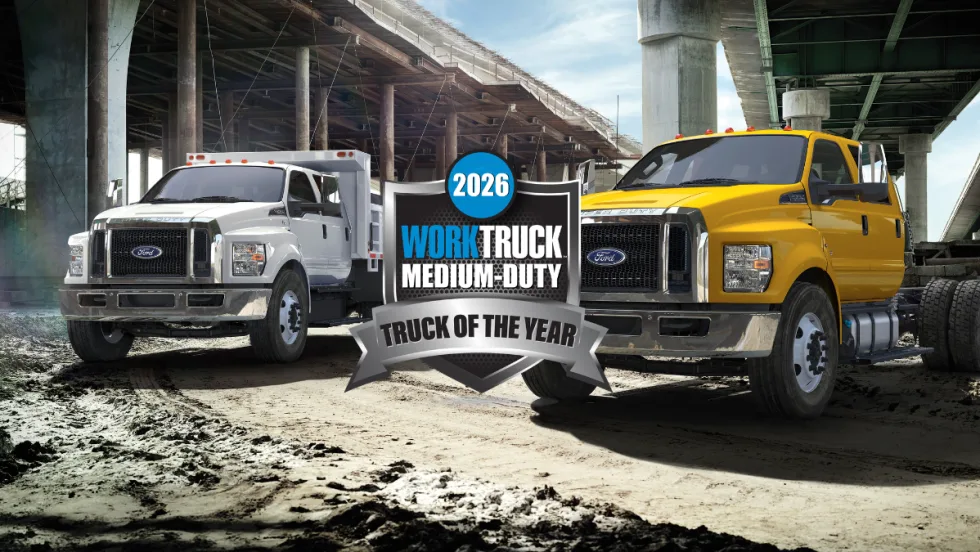 Two Ford medium-duty trucks, F-650 and F-750, parked under an overpass with a 2026 Work Truck Medium-Duty Truck of the Year award badge displayed.