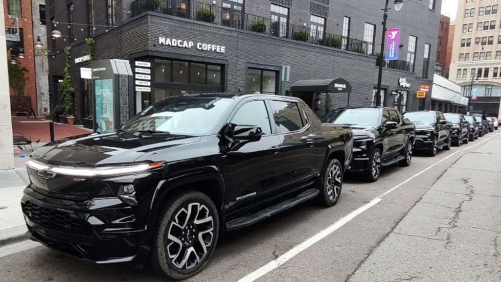 A row of black pickup trucks shown parked in downtown Detroit.