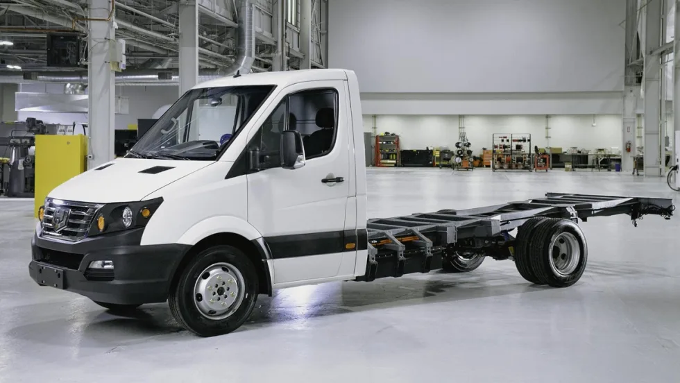 White chassis cab truck is parked inside a building facing left.
