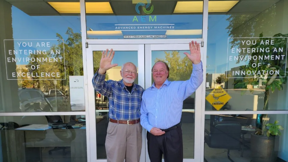 Robert and Ron Koelsch wave in front of the AEM headquarters building.