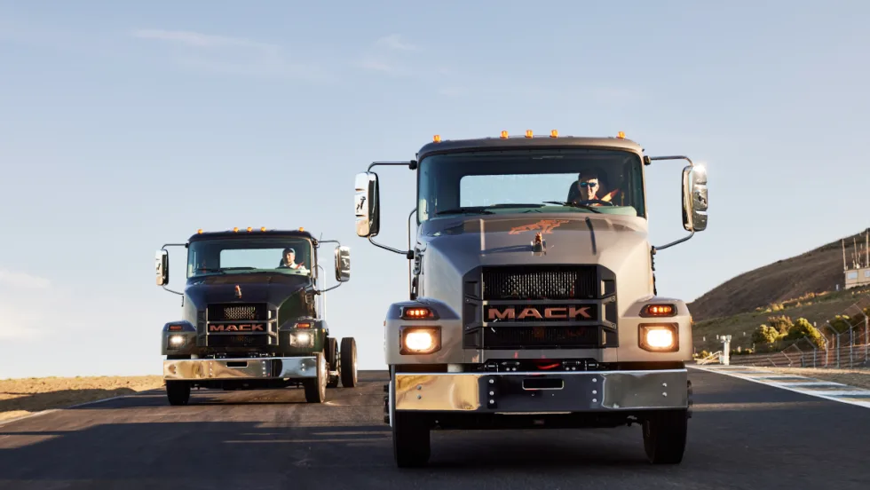 Two medium-duty chassis cab trucks driving toward the camera.