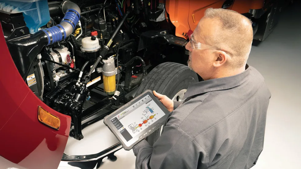 An man using a tablet to check the truck's engine.