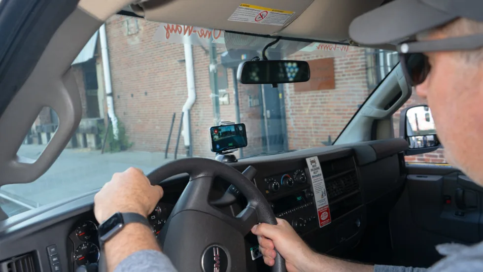 Image of a man behind the wheel of a truck with a dashboard camera in use.