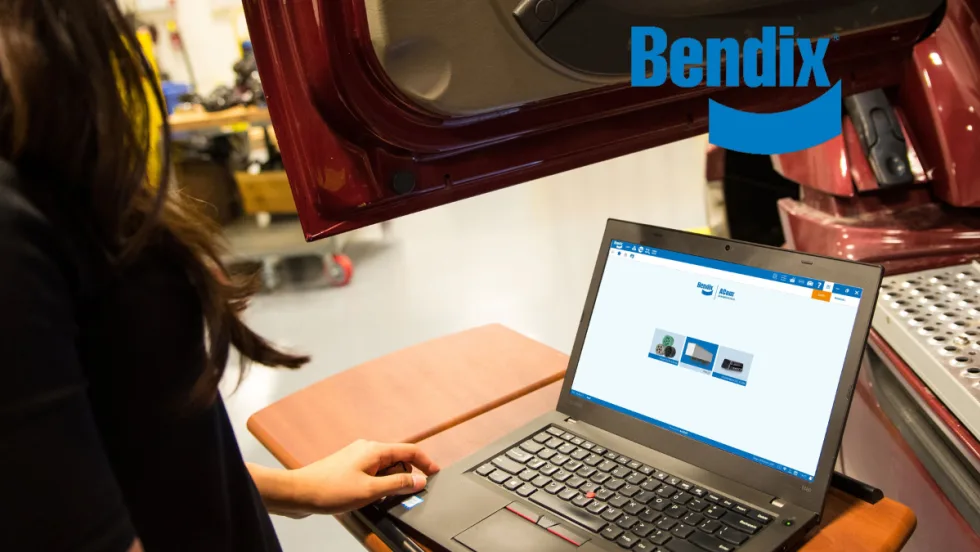 Image of woman using a laptop to diagnose a problem next to a vehicle.