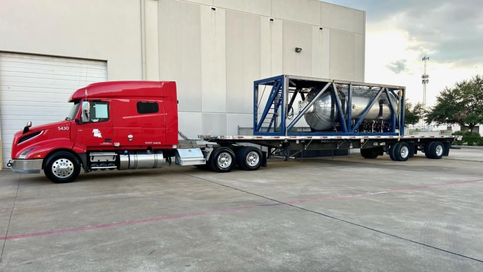 tractor trailer hauling large equipment on a flatbed trailer.