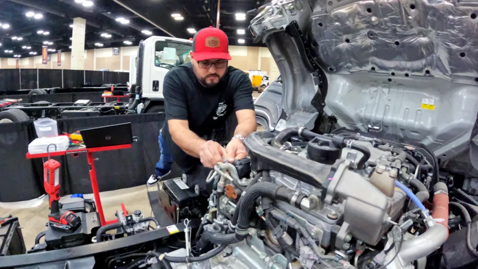 Truck technician works on the engine of a truck.