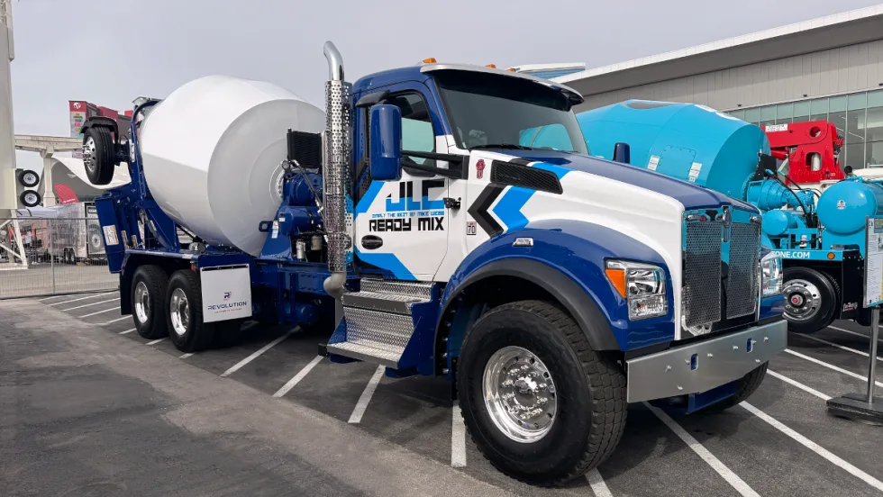 Photo of a concrete truck parked, blue and white cab, white mixer.
