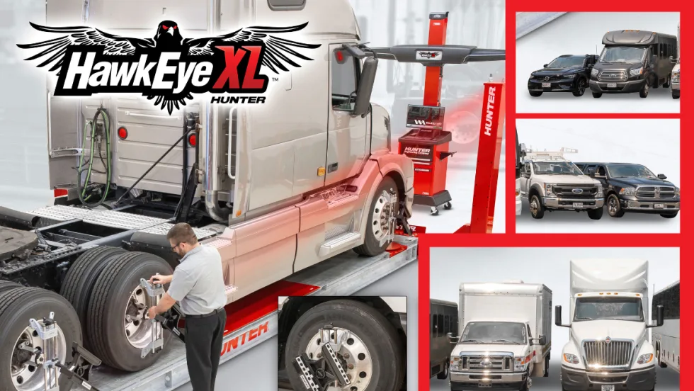 Tire technician working on a large truck tire with truck positioned on a wheel alignment system.