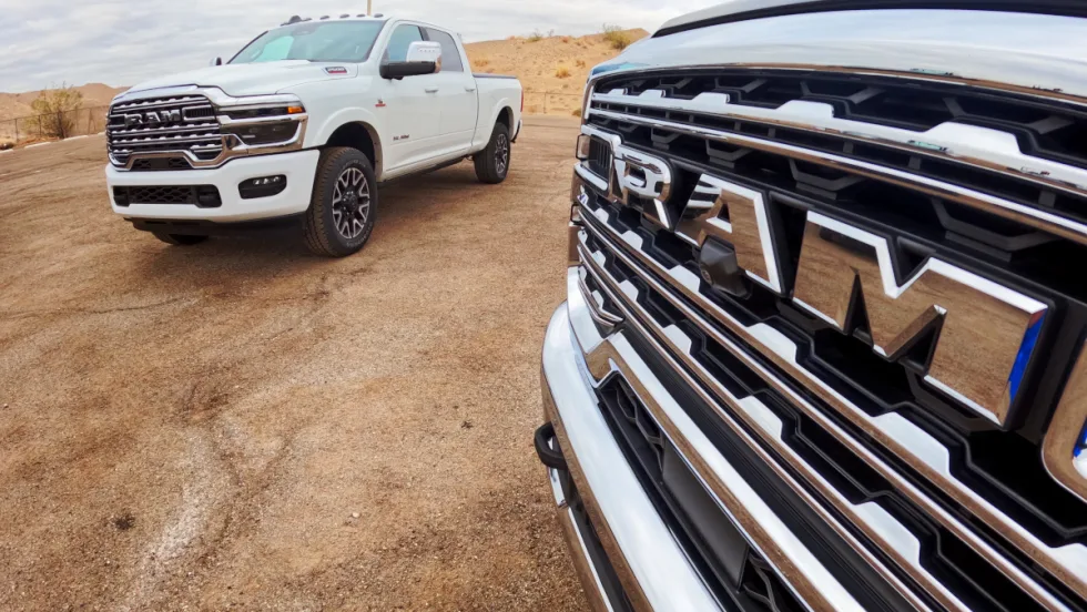 Close photo of front grille of a Ram truck, with another truck in the background