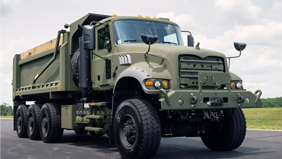 Mack military dump truck view from a low angle against a blue sky.