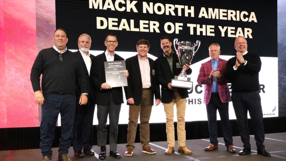 Group of businessmen on a stage presenting and receiving an award trophy.