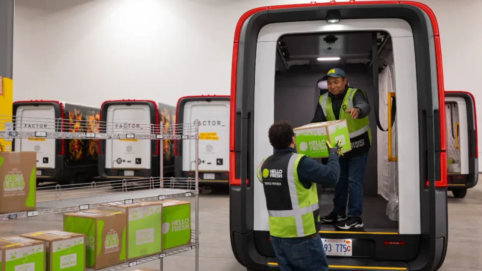 A Rivian electric van is loaded by a HelloFresh driver