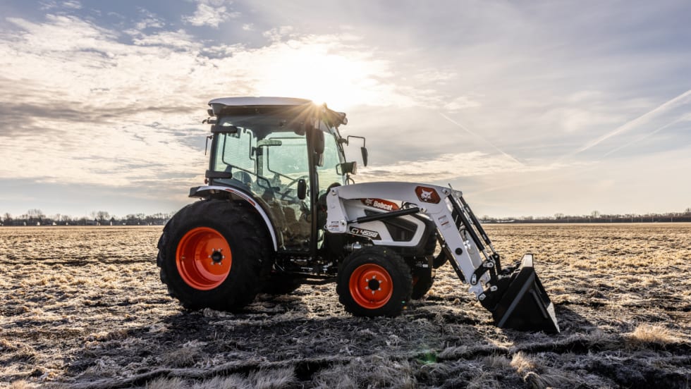 Bobcat tractor with front bucket parked in a field.