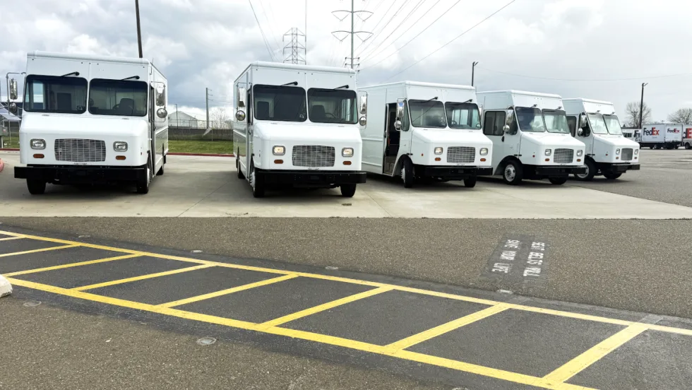 Five white step vans parked facing the camera.