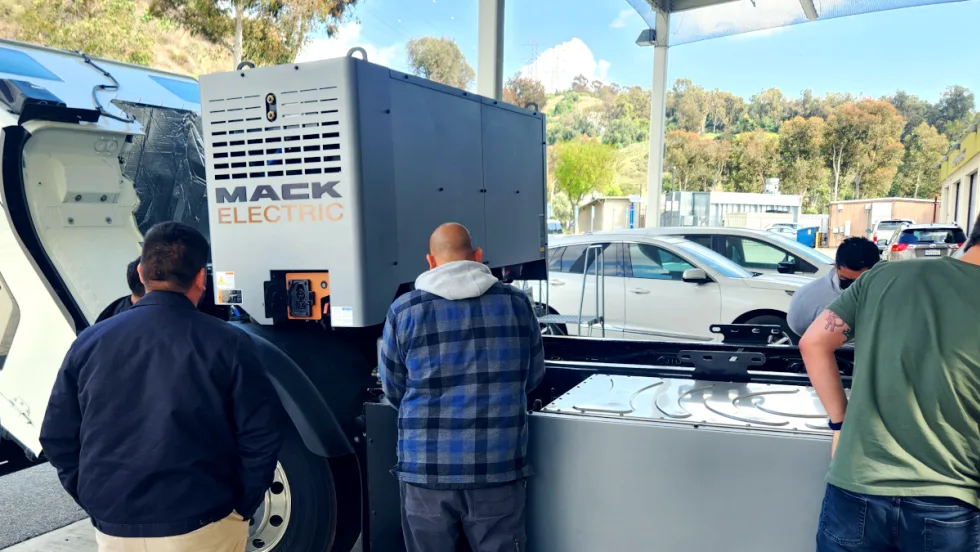 Students look over a Mack LR Electric chassis.