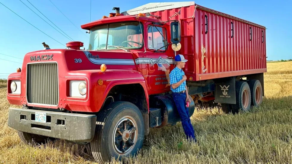 A red Mack Truck farm truck in a field.