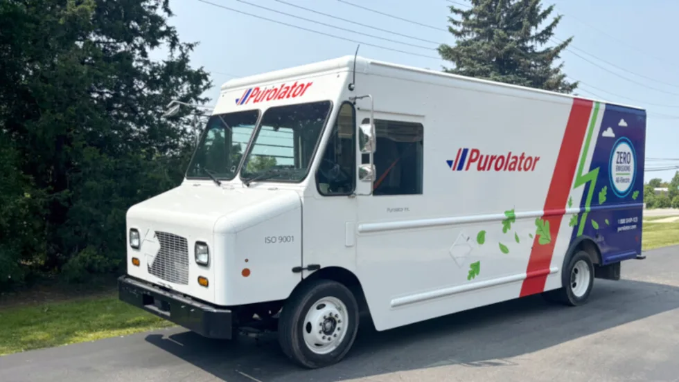 White electric step van with Purolator logo parked in a parking lot.