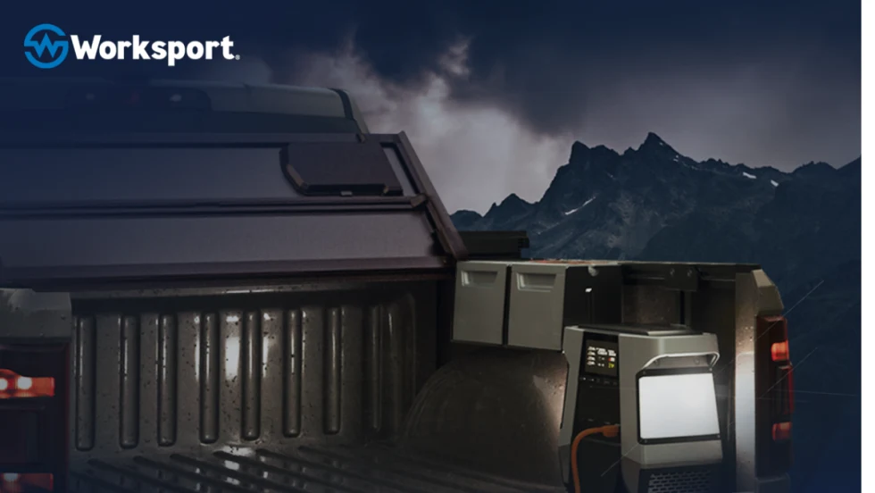 Pickup truck bed with tonneau cover folded back to the cab and a portable power station near the tailgate.