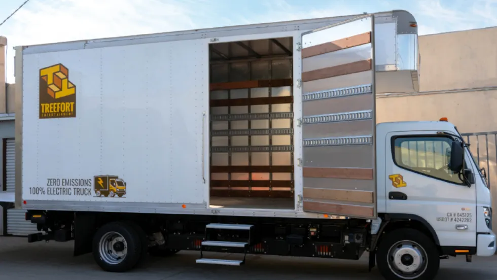 Medium-duty battery-electric box truck parked with side door open.