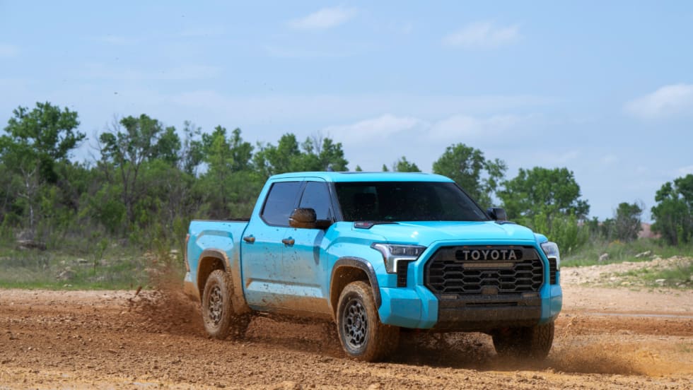 Light blue off road Toyota Tundra pickup truck driving on dirt.