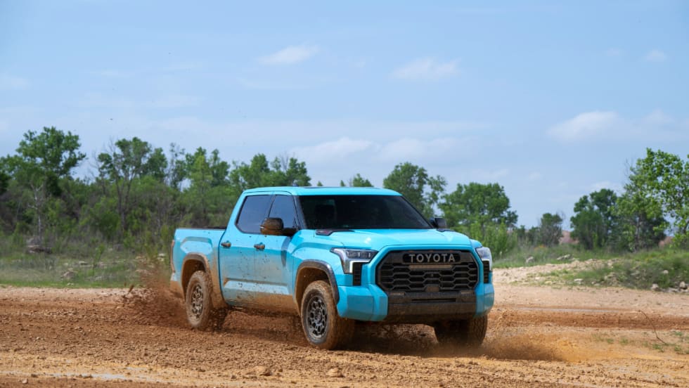 A 2026 Toyota Tundra TRD Pro in Wave Maker blue drives off-road, kicking up dirt, showcasing the truck’s off-road capability.
