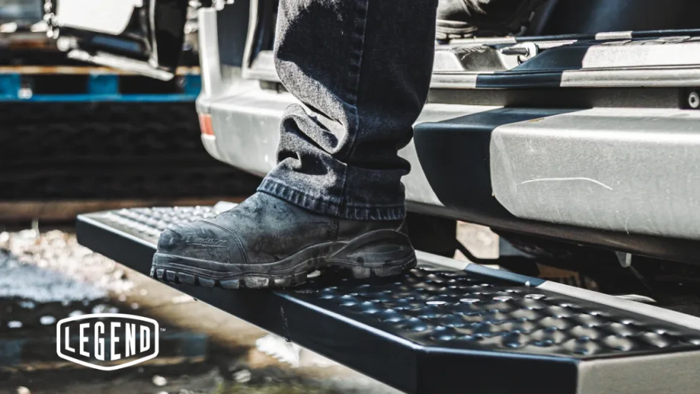 Work boot stepping onto Legend FixStep rear step with anti-slip steel tread in wet outdoor conditions, showcasing traction and durability.