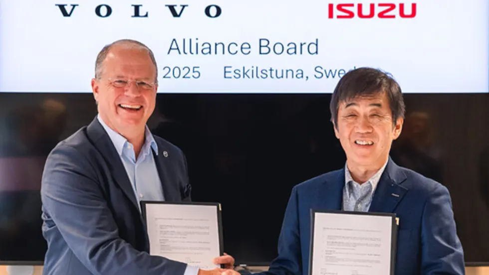 Two men in business attire shake hands after signing an agreement.
