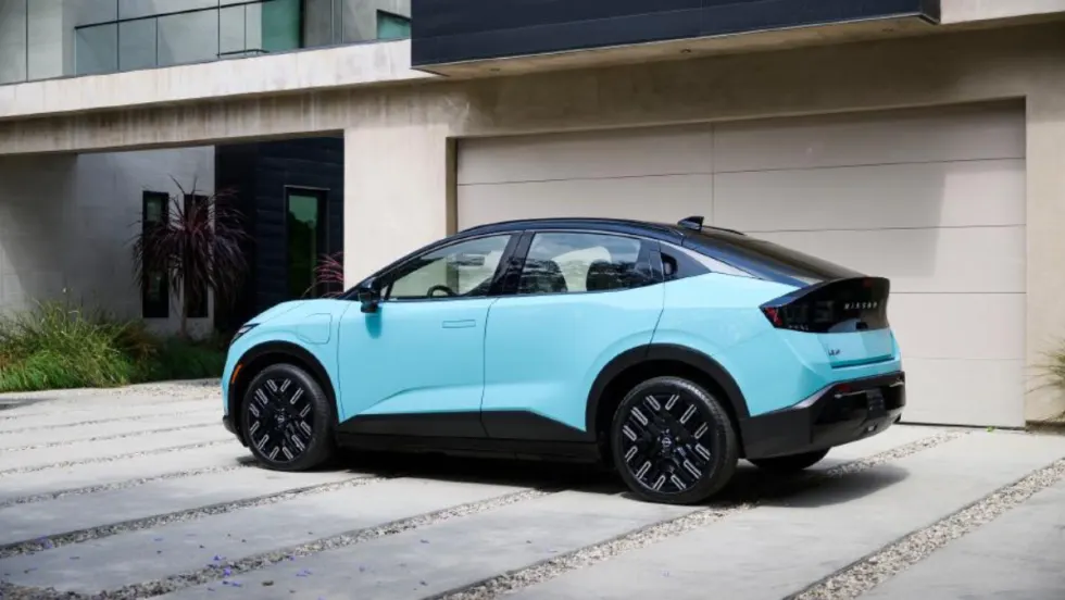 Light blue Nissan EV parked in front of a modern home garage, highlighting residential charging compatibility.