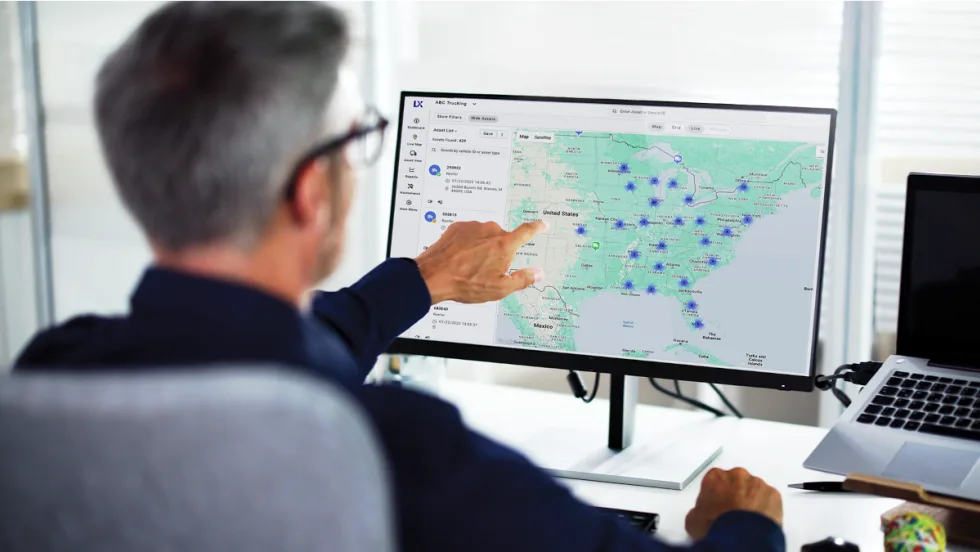 Man pointing to a map and data points on a computer screen.
