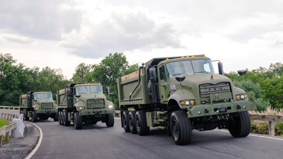 Three military dump trucks driving on a test track.