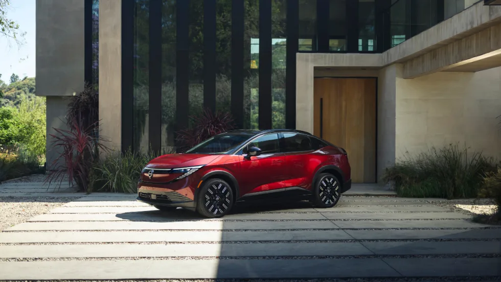 A red 2026 Nissan LEAF parked in front of a modern home.