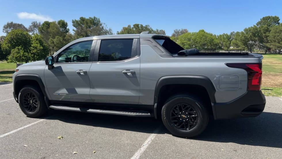 A gray Chevrolet Silverado electric pickup truck in the parking lot of a public park.