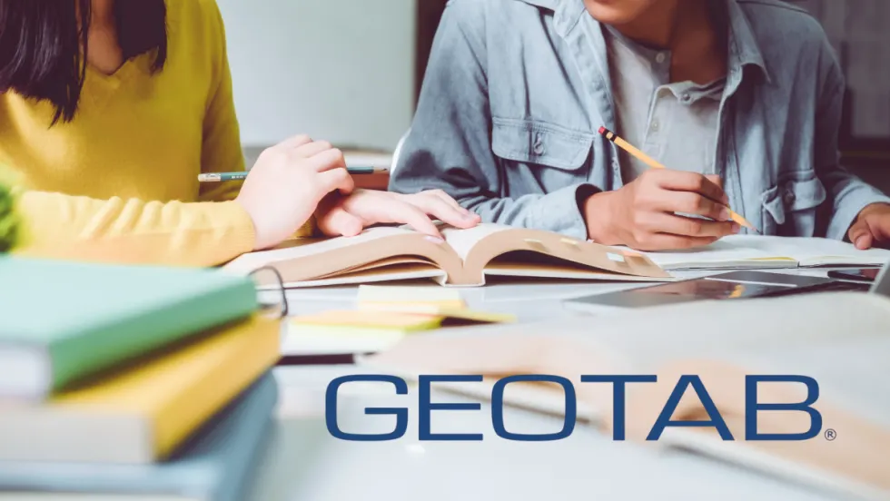 Two students study with books and notes at a desk. Geotab partners with Georgia Tech on $223K traffic data research to improve safety and urban mobility.