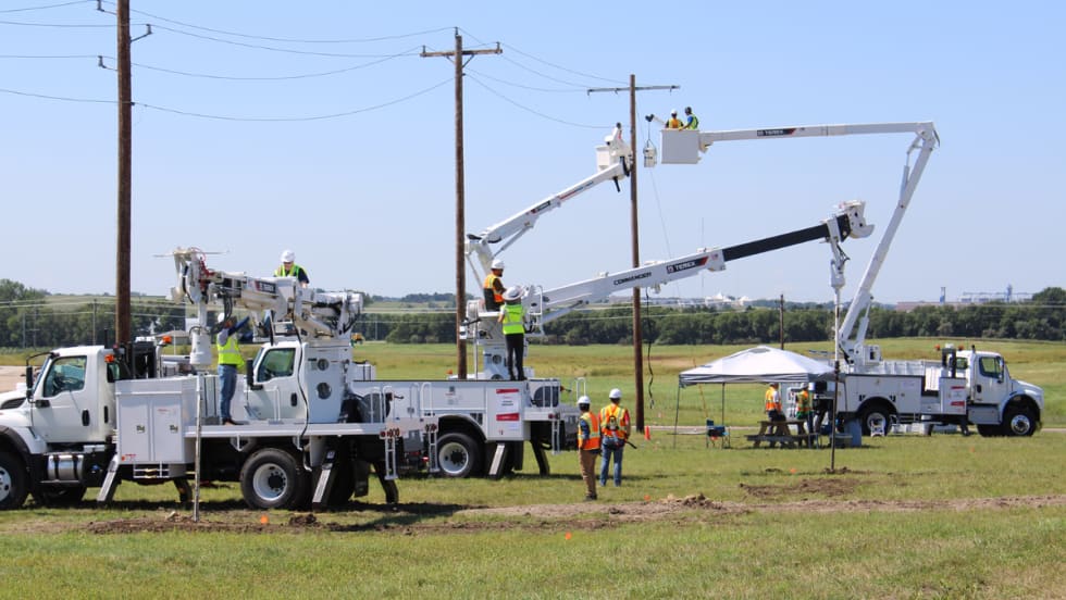 Utility workers operate Terex digger derricks and aerial devices in a field training session, practicing pole setting and aerial lifts during the Terex Utilities Hands-On Training event.