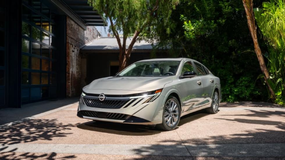 A silver 2026 Nissan Sentra parked in a courtyard, showcasing its redesigned front grille and headlights.