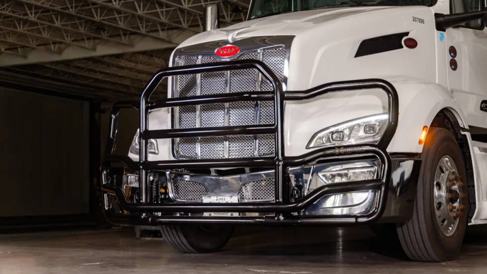 Black grille guard on front of a white tractor trailer, viewed from a front/side angle.