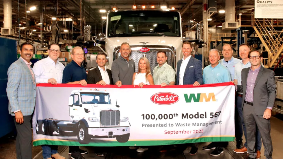 Group of Peterbilt, Waste Management, and Rush Enterprises leaders stand in front of a Peterbilt truck holding a banner celebrating the 100,000th Model 567 delivery in September 2025.