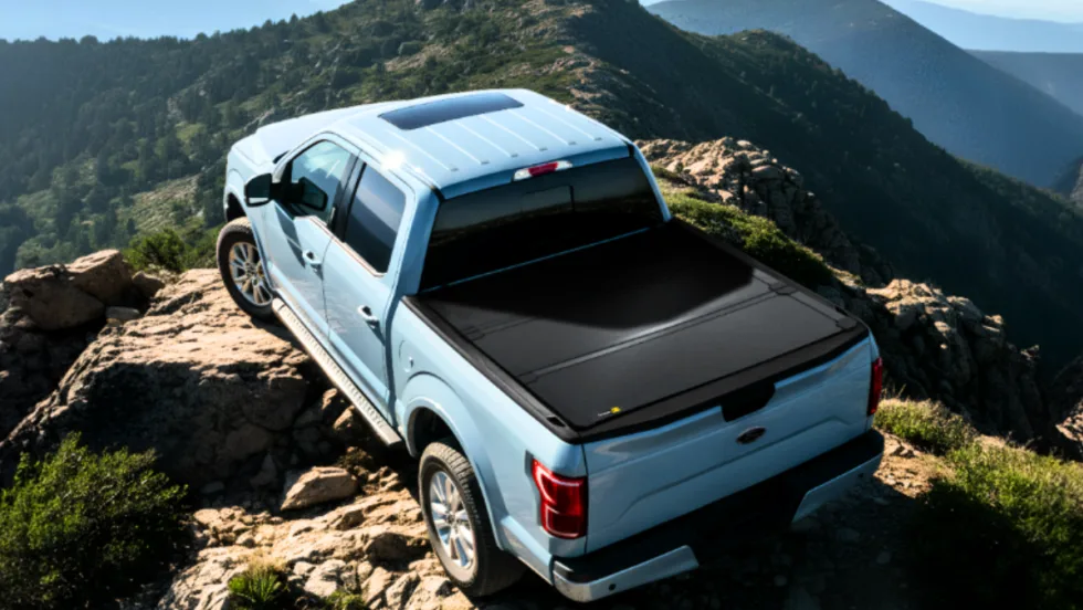 Light blue pickup truck with black tonneau cover in a mountain setting.