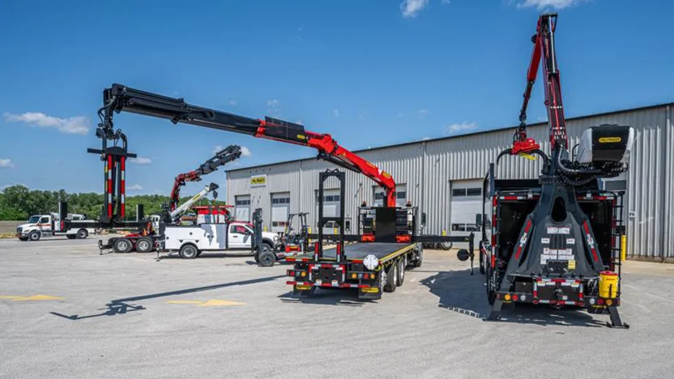 PALFINGER forestry trucks and a mechanic truck with crane parked outside a building.