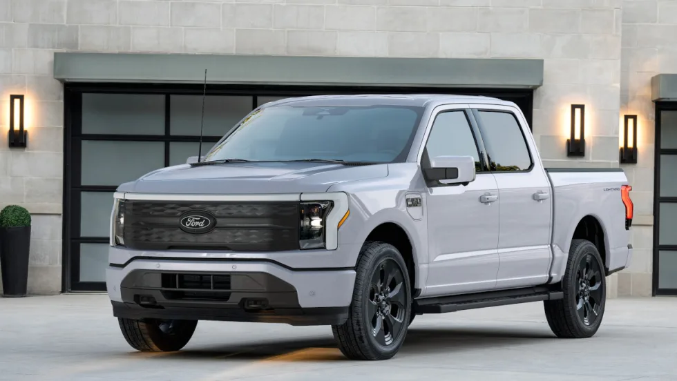 Silver Ford pickup truck parked in driveway of home in front of garage door.