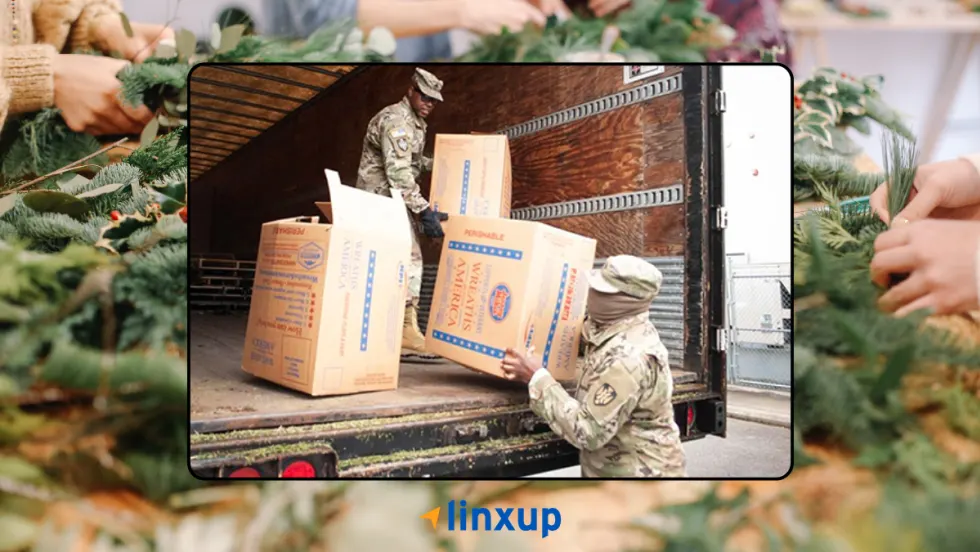 Service members unloading Wreaths Across America boxes from a truck as volunteers prepare wreaths, highlighting Linxup’s support and participation in honoring veterans.
