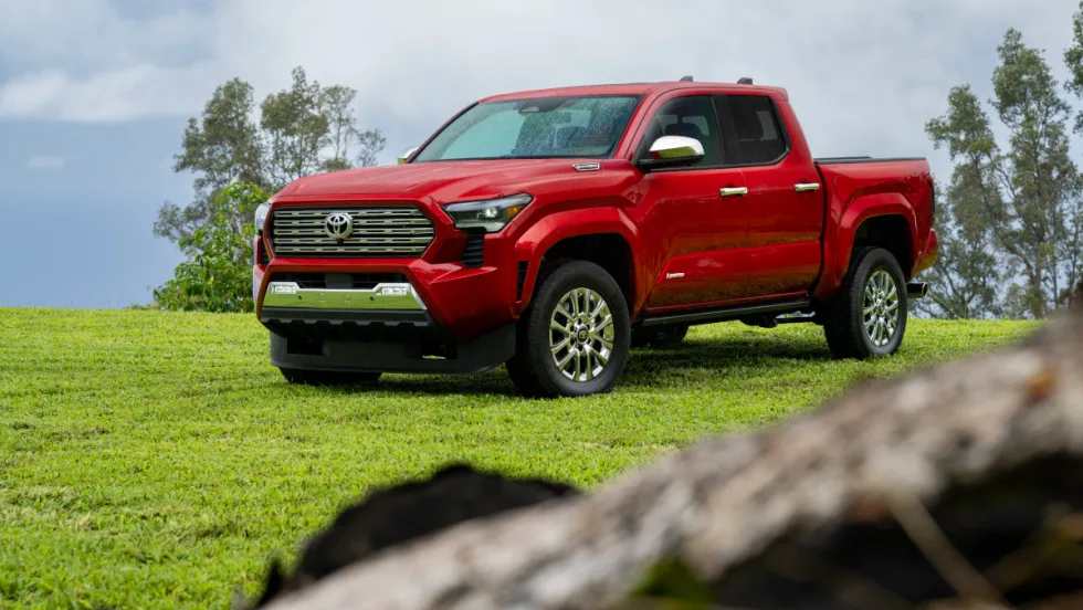 Red four-door Toyota pickup parked in a grassy area.