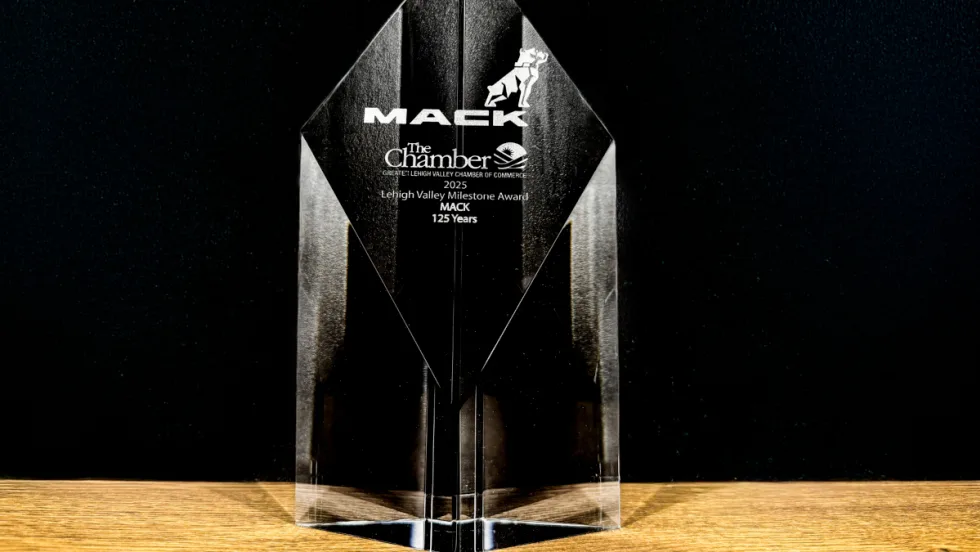 Photo of a glass looking clear award with name Mack Trucks set against a black background.