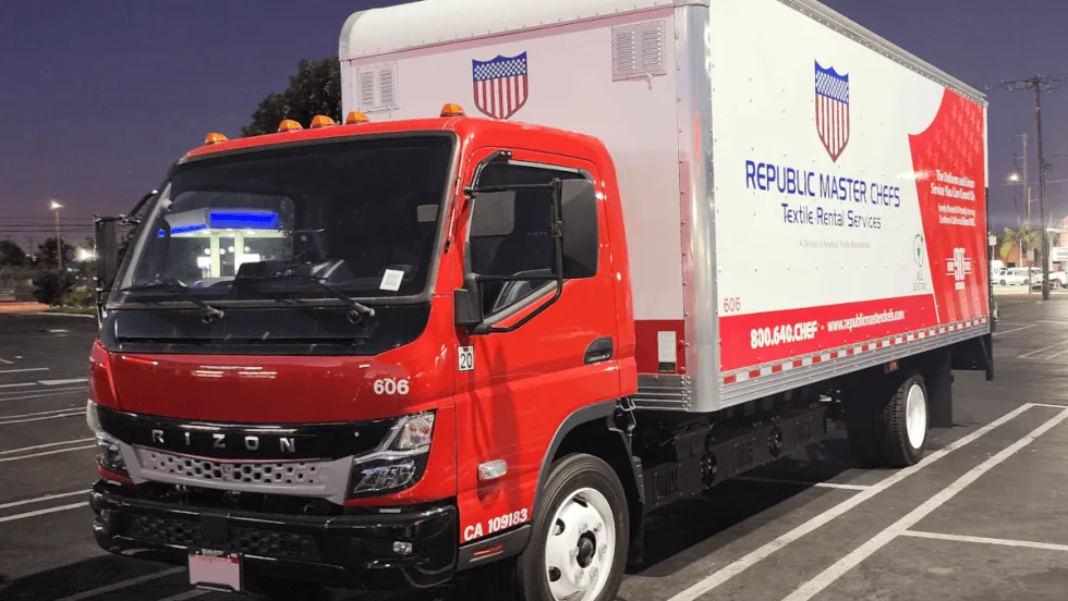 Box truck with a red cab parked in a parking space.